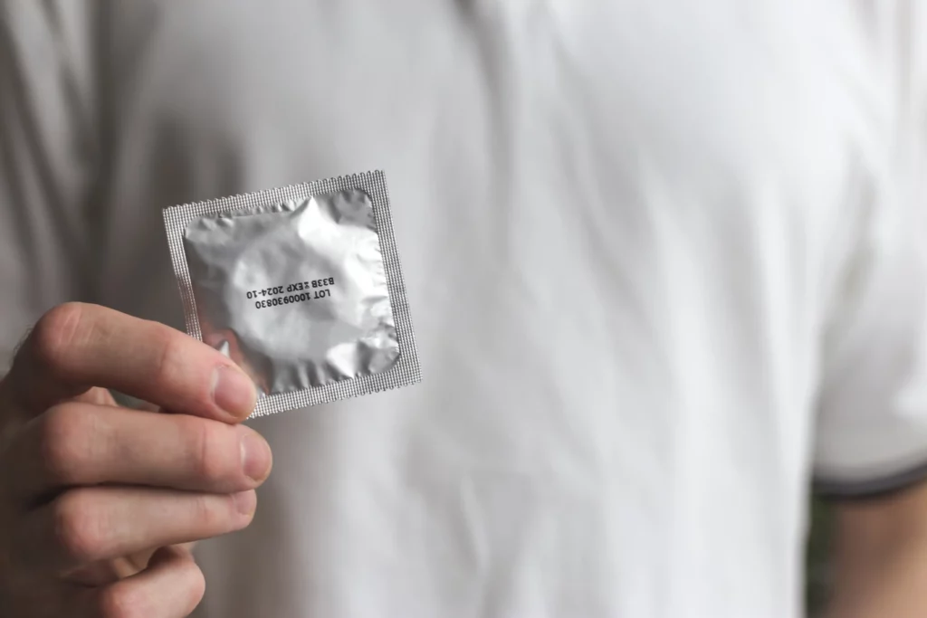 Homem segurando embalagem de preservativo